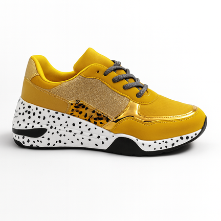 Gul modesneaker med guld detaljer og hvid sål med sorte prikker.