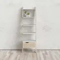 En minimalistisk bogreol i stigestil i let træ med fem hvide hylder er sat op ad en almindelig væg. En lille plante i en hvid potte stilles på en af hylderne. Bogreolen står på et lyst trægulv.