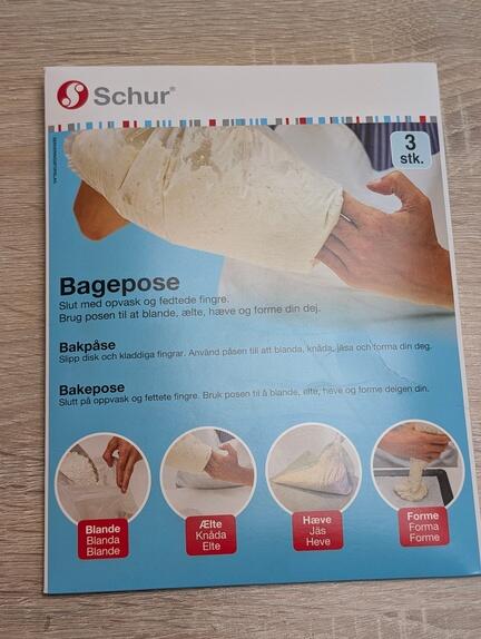 Emballage af Schur Bagepose, viser brugsanvisning til bagning. Forsiden viser en hånd, der holder dejen i en pose. Trin omfatter: blend ingredienser, ælt dejen, lad hæve og form. Teksten er på dansk og engelsk.