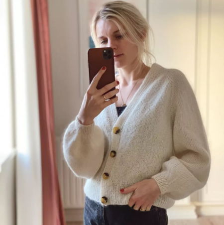 petiteknit ifoert sin strikkede model balloncardigan i hvid hun tager et billede af sig selv
