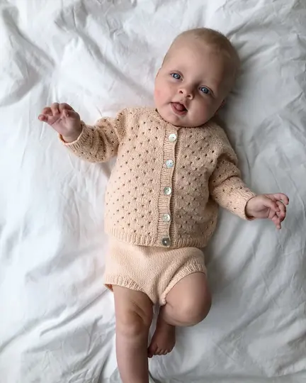Baby iført Ellens Legesæt fra PetiteKnit strikket i Merci fra Filcolana – cardigan og blebukser