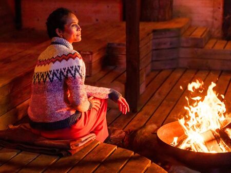 Bagsiden af Betula sweater ses i bålets skær. En varm sweater i Peruvian og Alva med inspirerende birkemønster.