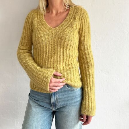 Kvinde iført Cascade Blouse af Odd Row i gul. Strikket i Highland & Silk Mohair fra Isager med V-hals og snoningsdetaljer.