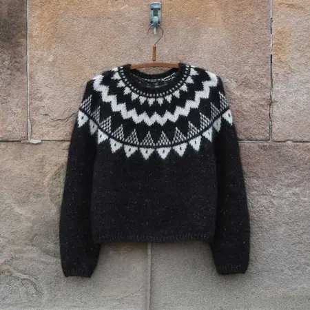 Anne Ventzels Selene Sweater i mørk brun og hvidt mønster hænger på væg