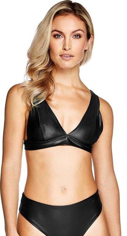 En kvinde med langt, bølget blondt hår bærer en sort bikini med dyb V-udskæring og matchende underdel, mens hun står på en almindelig hvid baggrund.