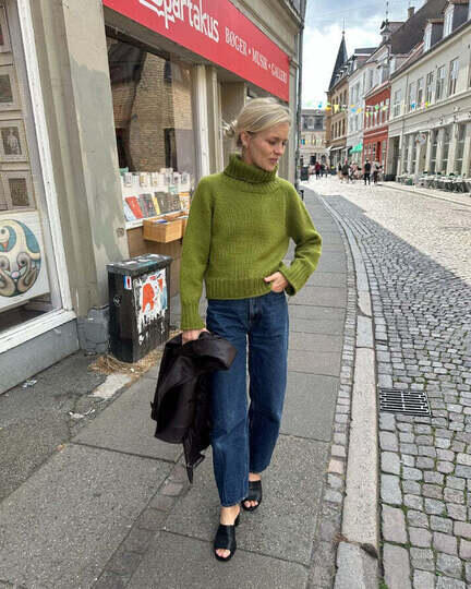 Kvinde iført Amy Sweater fra PetiteKnit – grøn strik med rullekrave strikket oppefra og ned