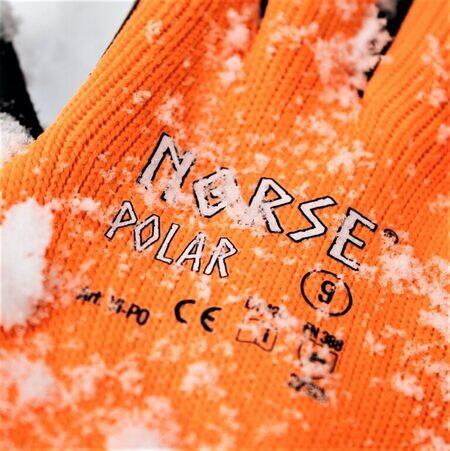 Et nærbillede af Norse Polar arbejdshandsker i sort og orange, dækket af et lag sne. Dette viser handskernes evne til at håndtere kolde forhold med stil og funktionalitet.