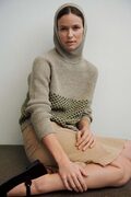 model kigger ind i kameraet hun bærer en agnes sweater designet af tine rousing strikket i isager garn