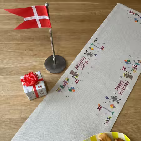 Broderet Fødselsdagsløber fra pomp stitch med flag og gaver og små figurer