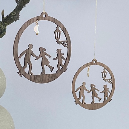 Familie på skøjter juleornament i træ ophængt i gren – design i eg og valnød med måne og gadelygte
