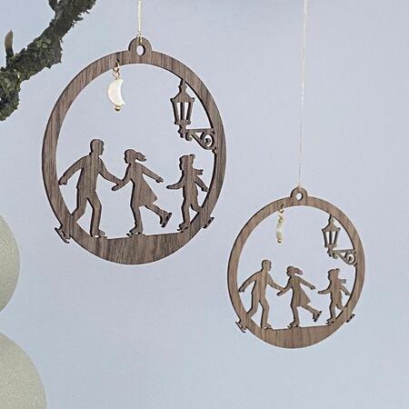 Familie på skøjter juleornament i træ ophængt i gren – design i eg og valnød med måne og gadelygte