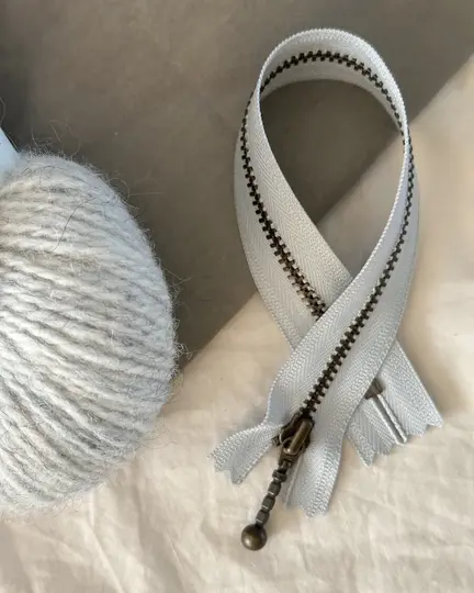 petiteknit zipper laengde 23 cm farve havskum zipper ligger paa et bord