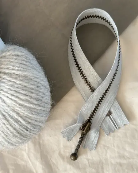 petiteknit zipper laengde 23 cm farve havskum zipper ligger paa et bord