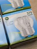 Nærbillede af emballerede pærer mærket Soft Style Lighting. Æsken noterer 28W, 370 Lumen, E 27, Stor sokkel, Krone, Dæmpbar og Energibesparende, hvilket indikerer energibesparende, dæmpbare pærer med stor fatningsstørrelse.