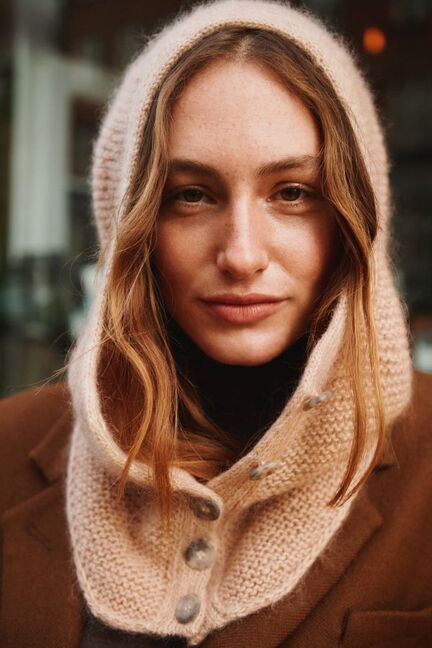 Andrea Hood balaclava i lys sandfarvet Isager Tweed og Silk Mohair, fotograferet i tæt portræt over brun frakke med tydelige knapper i forkanten.
