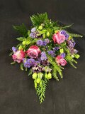 Klassisk bårebuket til begravelse med rosa roser og lilla nuancer – stilfuld og værdig afsked. Fra Kaffeblomsten ved Helena.