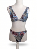 Mannequin iført en todelt bikini med et blomstermønster i blå, brun og rød. Overdelen har en dyb V-udskæring og flæset stropper, mens underdelen har et højt skåret snit.