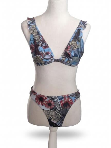 Mannequin iført en todelt bikini med et blomstermønster i blå, brun og rød. Overdelen har en dyb V-udskæring og flæset stropper, mens underdelen har et højt skåret snit.