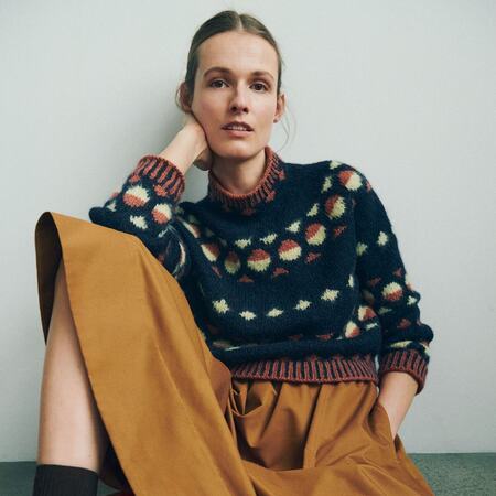 model sidder op af vaeg ifoert moerk udgave af gunta sweater fra helga isager