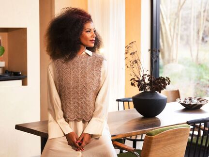 Rimfrost slipover set forfra. Strikket i tre tråde Tilia og Paia, med detaljerigt bladmønster, båret af model indendørs ved et spisebord.