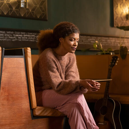 kvinde paa baenk ifoert audry bluse fra filcolana strikket i arwetta og tilia roede farver