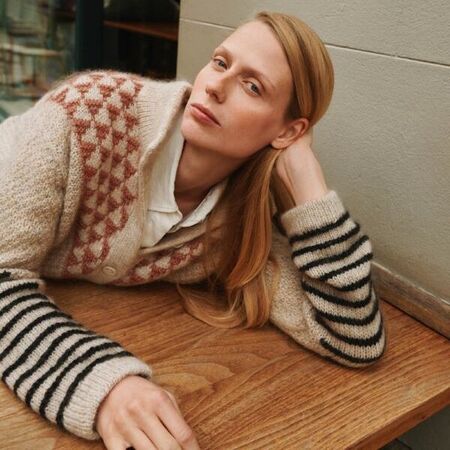 Model iført Alice Jacket, designet af Odd Row, fra Isager Archives 2, strikket i beige Jensen Yarn og Silk Mohair med gammelrosa trekantmønster og sorte striber på ærmerne. Jakken vises afslappet i bymiljø